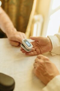 A close-up of hands using a pulse oximeter to monitor health indoors.